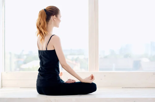 Mujer haciendo yoga cerca de la ventana ejercicio físico estilo de vida — Foto de Stock