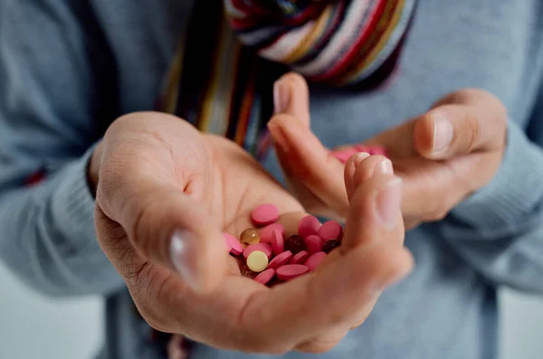 Sjuk man i en tröja med piller i handen hälsoproblem ljus bakgrund — Stockfoto