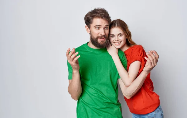 Мужчина и женщина в разноцветных футболках обнимают студию — стоковое фото
