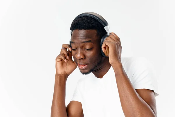 Hombre de aspecto africano en auriculares amante de la música fondo de luz — Foto de Stock