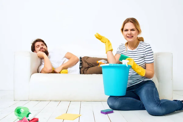 A man lying on the couch housewife cleaning the house — Stock Photo, Image