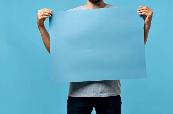 Schöner Mann blaues Banner in der Hand leeres Blatt blauer Hintergrund — Stockfoto