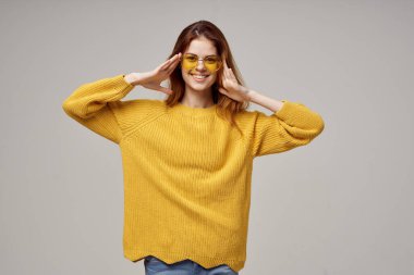 Sarı gözlüklü güzel kadın eğlenceli yaşam tarzı ışık arka planında poz veriyor.