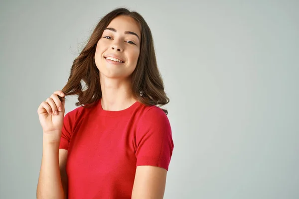 Brunett innehav hår poserar mode röd t-shirt studio — Stockfoto