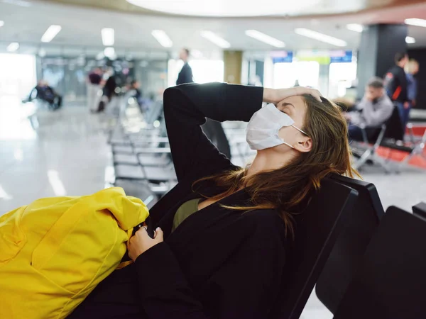 Усталая женщина с закрытыми глазами медицинской маски ждет полета у пассажира аэропорта — стоковое фото
