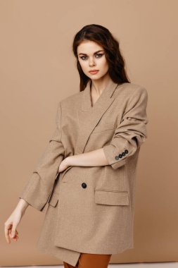 Paltolu ve pantolonlu seksi esmer bej arka planda.