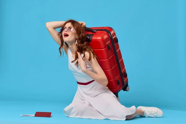 Vrolijke vrouw met rode koffer zitten op de vloer emoties geïsoleerde achtergrond — Stockfoto