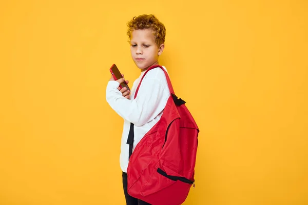 Vidám iskolás fiú piros hátizsákkal hívások telefonon Stúdió tanulás koncepció — Stock Fotó