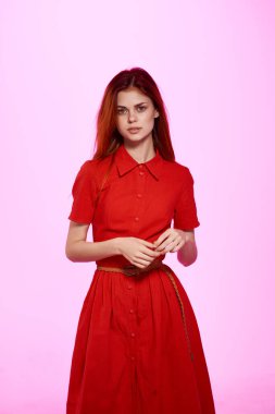 Pembe arka planda poz veren kırmızı elbiseli güzel bir kadın. Yüksek kalite fotoğraf