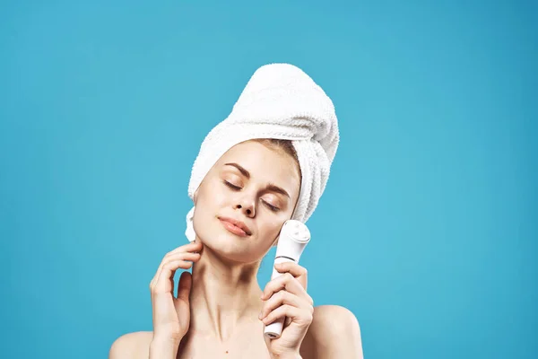 Frau mit nackten Schultern mit einem Handtuch auf dem Kopf Gesichtsmassagerpflege — Stockfoto