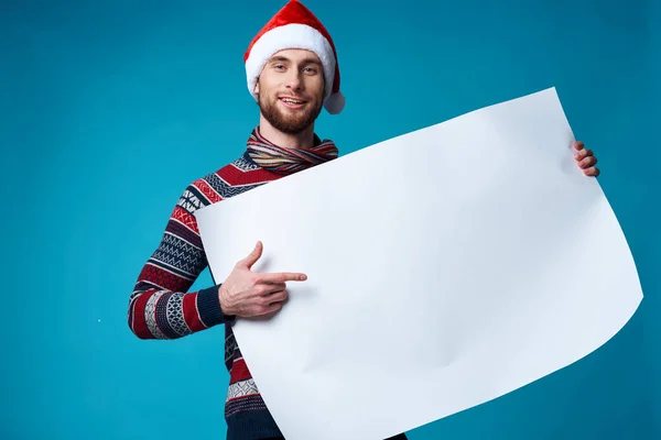 Cheerful man in a santa hat holding a banner holiday blue background — Stock Photo, Image
