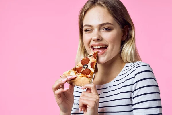 Женщина в полосатой футболке с пиццей в руках закуски быстрого питания розовый фон — стоковое фото