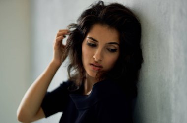 Pencerenin yanındaki siyah elbiseli kadın lüks moda pozu veriyor.