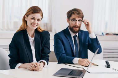 Meslektaşlar laptop ofis teknolojisi önünde birlikte çalışırlar.