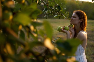 Elma ağacının yanında beyaz elbiseli bir kadın.