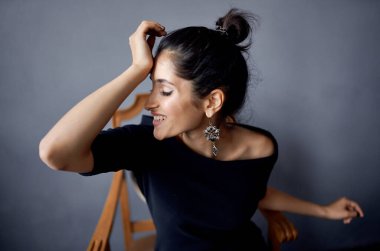 Sandalyenin yanında siyah elbiseli güzel bir kadın lüks moda stüdyosunun yanında.