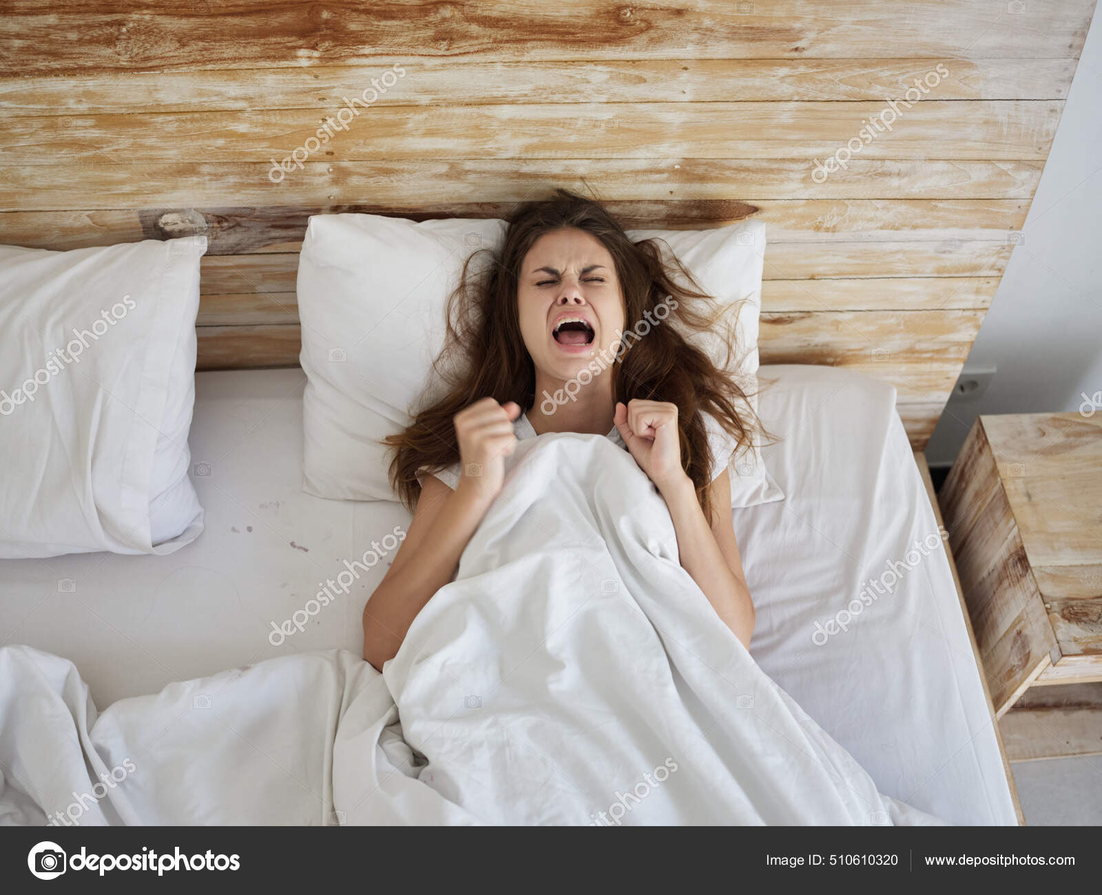 Screaming woman with open mouth lies in bed under the covers Stock ...