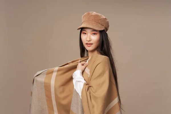Kvinna i skjorta och i en beige capes hatt på huvudet brunett asiatisk utseende — Stockfoto