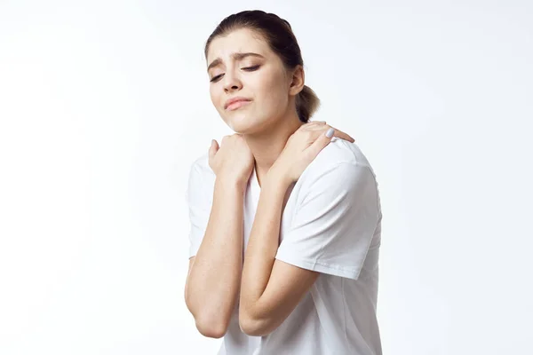Woman in white t-shirt holding shoulders neck pain health problems discomfort — Stock Photo, Image