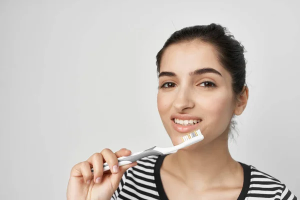 Mulher alegre escovar os dentes com uma escova de dentes fundo leve — Fotografia de Stock