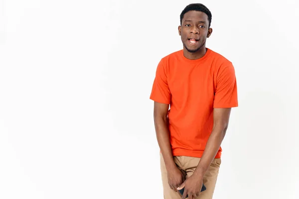 Afrikansk kille i orange T-shirt med mobiltelefon och byxor — Stockfoto