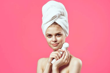 Kafasında havluyla elinde masaj aleti olan bir kadın.