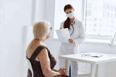 Hemşire steteskop tarafından muayene edilen yaşlı kadın hasta.