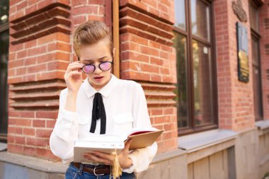 Gözlüklü bir öğrenci kitap eğitimi alarak şehirde dolaşıyor.