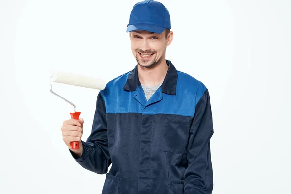 A man in a working uniform painting the walls repairing the house — Stock Photo, Image