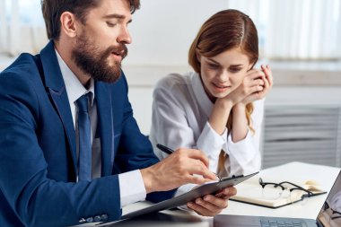 Erkek ve kadın yöneticiler dizüstü bilgisayar ofis teknolojisinin önünde masada oturuyorlar.