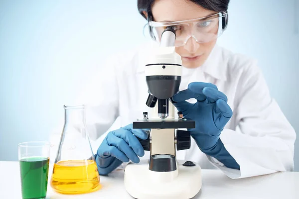 Женщина смотрит через микроскоп химического раствора лабораторные исследования биотехнологии — стоковое фото