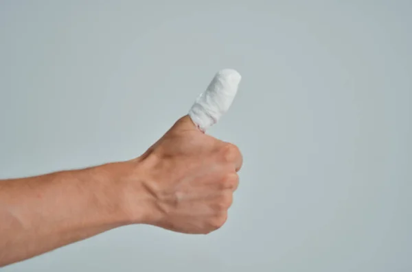 Paciente masculino vendado lesión en la mano a los dedos fondo claro —  Fotos de Stock