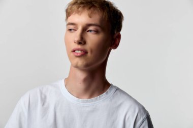 Sade erkek manken stüdyoda düşünceli bakışlar, yumuşak ışıklandırma ve moda, yaşam tarzı ve yaratıcı stok görselleri için basit kompozisyon ile duruyor.