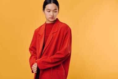 Kırmızı dış görünüşlü kadın modelin portresi turuncu stüdyo arkaplanına bakıyor, sokak giyimi tarzı sergileniyor, minimal tasarım ve modern günlük kıyafet modası..