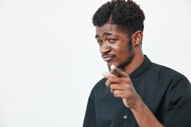 Siyah tişörtlü, koyu tenli, kıvırcık saçlı, beyaz arka planda kendine güvenen genç bir Afro-Amerikalı. İfade, jest ve sıradan bir portre.