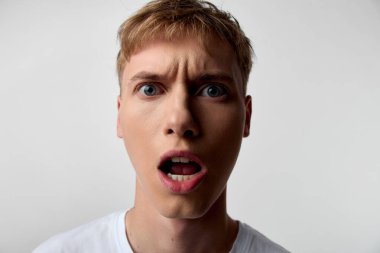 Şaşırmış, geniş gözlü, ağzı açık, stüdyo ışıklandırması, tarafsız arka plan, yoğun duygu ve hisse senedi kullanımı için beklenmeyen an gösteren şok olmuş bir adamın etkileyici yakın çekimi.