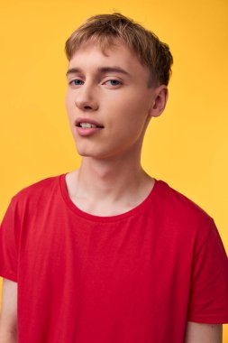 Canlı sarı bir duvara karşı kırmızı tişörtlü sıradan bir moda çekimi, parlak stüdyo ışıkları, temiz arka plan, minimal stil, çağdaş sokak kıyafetleri..