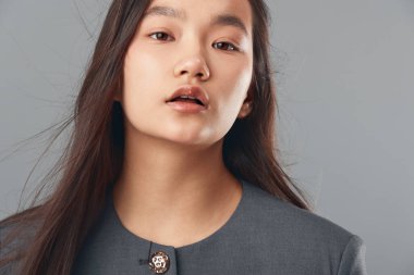 Düz, uzun saçlı, asgari makyajlı gri arkaplanda duran kadın model stil, zarafet ya da profesyonel portre için..