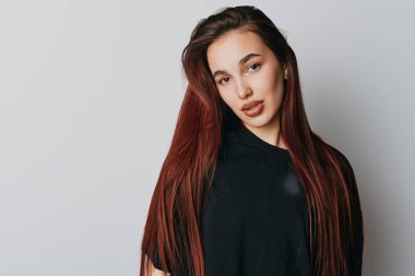 Siyah bluz giyen, düz kızıl saçlı genç bir kadının portresi. Profesyonel fotoğraf stüdyosundaki doğal görünüş ve tarafsız arkaplanda rahatlamış yüz ifadesi..