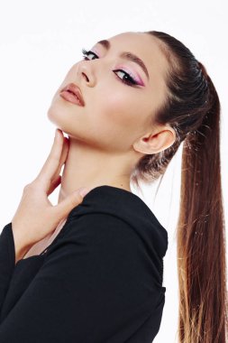 Siyah bluz giyerken parlak pembe göz makyajı ve parlak at kuyruğu yapan genç moda kadınının portresi. Temiz beyaz arka plan rengarenk, vahşi, yaratıcı güzelliği vurgular..