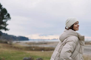 Açık hava portresi, yastıklı bir palto ve örgü bir bere takan göl kenarındaki ufka bakan sakin bir manzara ve serin bir esinti..
