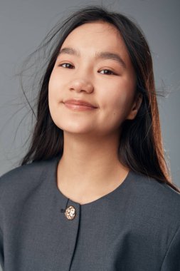 Uzun siyah saçlı genç kadın rahat ve nazikçe gülümsüyor. Günlük kıyafetler, doğal görünüş ve doğal cilt. Güzellik ve yaşam tarzı için tarafsız bir zemin..