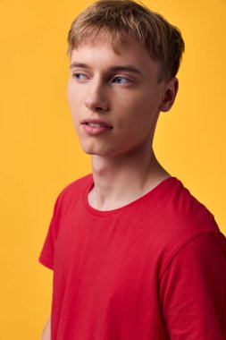 Parlak sarı bir zeminde kırmızı tişört giyen genç bir adamın günlük yaşam tarzı, en az stil, moda ve gençlik ifadesine odaklanmış, pazarlama ve editoryal kullanım için uygun modern titreşim