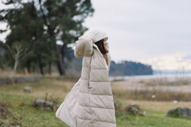 Suyun, rüzgarın süpürdüğü manzaranın, rahat hava modasının, soğuk havanın, parkın ve uzak sahillerin sakin atmosferinin, doğayı keşfetmesinin, sokak havasının titreşimlerinin olduğu bej kaplı bir palto.