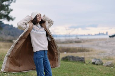 Kadın açık hava paltosu rüzgarı sonbahar yaşam tarzı günlük süveter, açık ufukta esintili açık hava manzarası, sakin hava, doğal ortam ve nazik sahil ışığı..