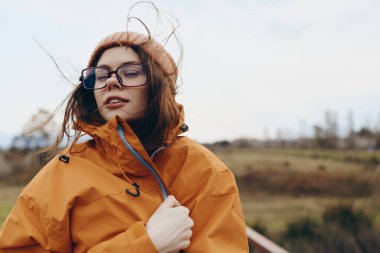 Sonbahar ceketli, gözlüklü, gözleri kapalı, sakin ve huzurlu bir kadın yaşam tarzının yakın çekimi. Açık hava aktivitesi, doğa ve günlük tarz kavramı.