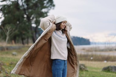 Kadın, palto, battaniye, açık hava, sonbahar, sıcacık bir palto giymiş, su kenarına yakın duran, temiz havada günlük kazak ve kot giyen bir kadınla samimi bir an.