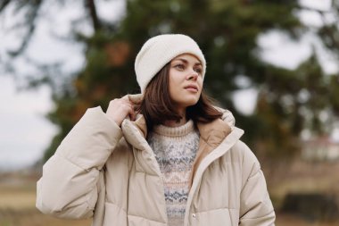 Sıcak manken ve örgü süveter giyip dışarıda poz veren rahat ruh hali, sessiz tonlar, hafif rüzgar, kış mevsiminin başlarında giyilen rahat kıyafetler ve modern sokak tarzı portre.