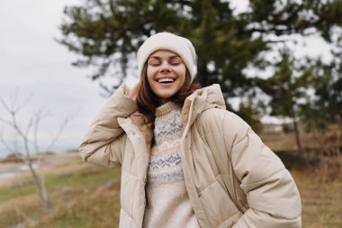 Sıcak bir palto giyen mutlu bir kadının portresi ve açık havada soğuk havanın tadını çıkaran örgü bir şapka.