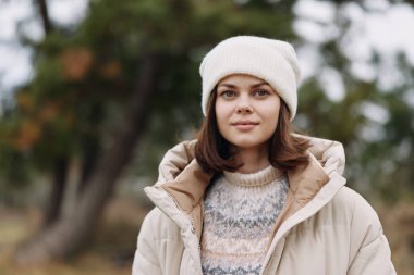 Örgü süveter ve bereli bir kadın portresi. Parkta çıplak ağaçlar, rahat bir ruh hali ve kış tarzı..